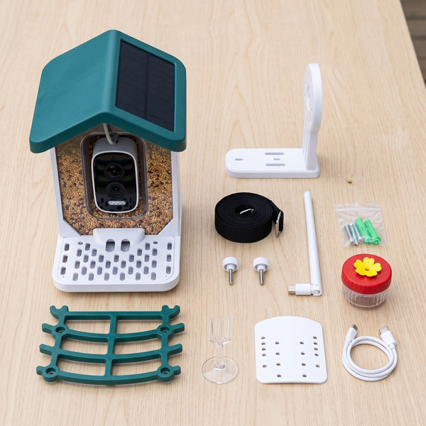 Everything from the box laid out on a wooden table: the feeder, the perch, the bracket, the strap, the antenna, the screws, the jar and the fork